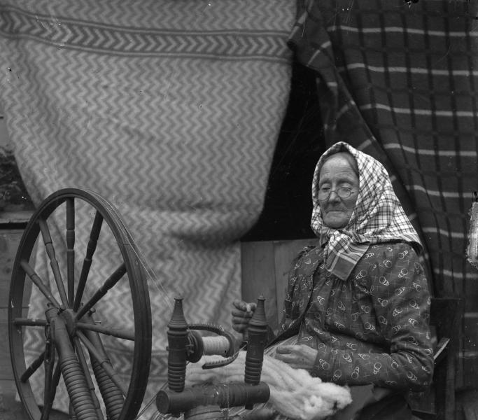 Kvinna som sitter vid en spinnrock och spinner. Foto: Pers Stjernberg, ur Kulturens samlingar. 