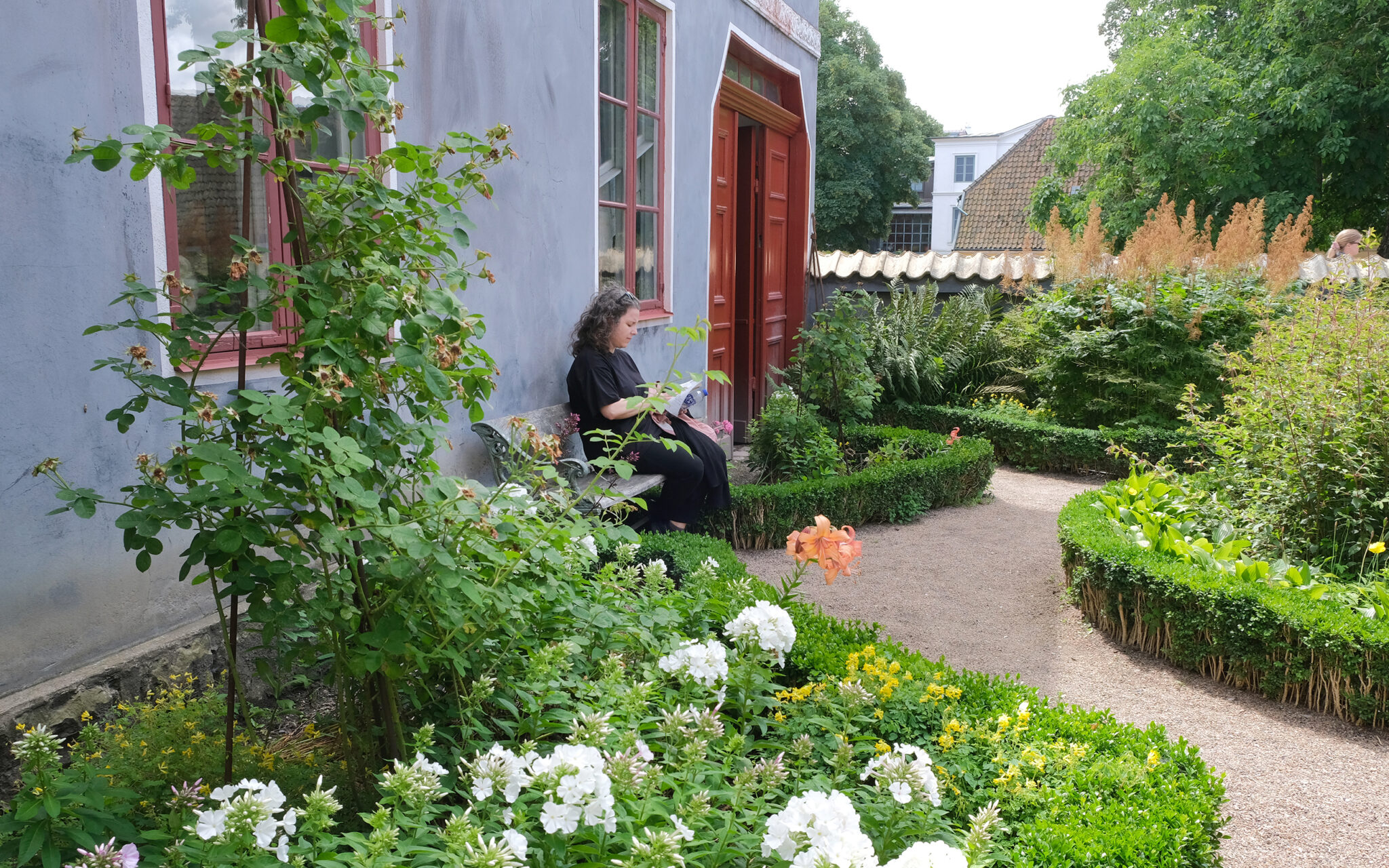 Kvinna sitter på en bänk i en trädgård.